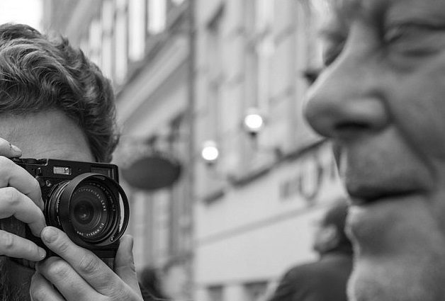 Fotógrafo captando de cerca el rostro de un hombre en una escena urbana en blanco y negro