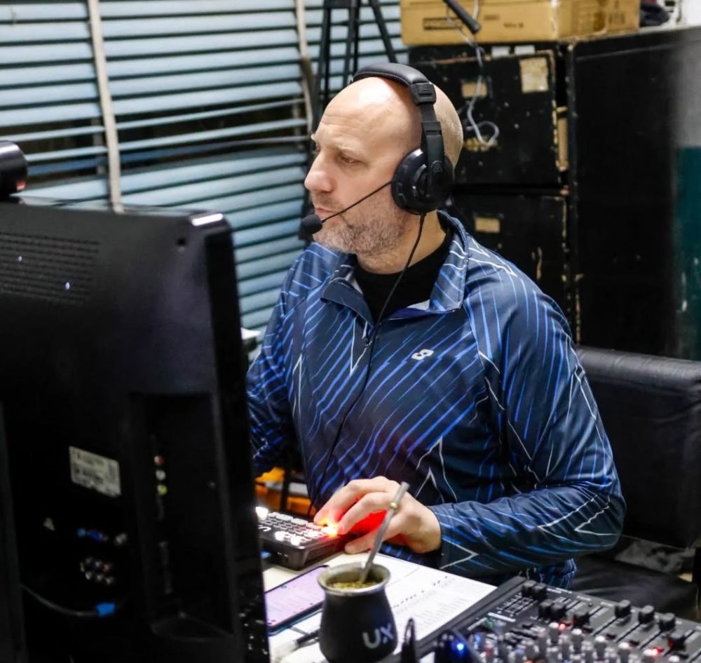 Germán Langone operando una consola de transmisión con auriculares en una cobertura deportiva