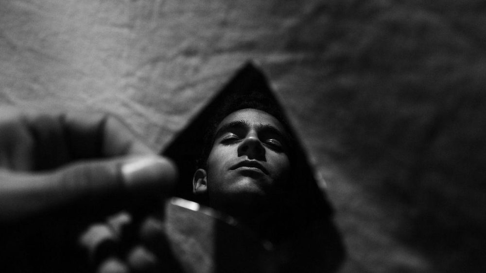 Reflejo de una persona en un espejo triangular que distorsiona la imagen en un entorno urbano