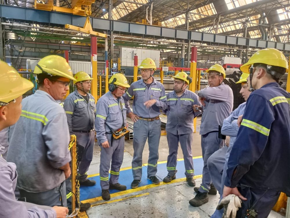 Obreros con cascos en asamblea dentro de una fábrica metalúrgica