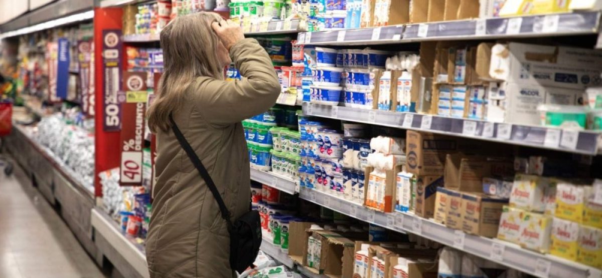 Persona observando precios en una góndola de supermercado en un contexto de caída del consumo en Argentina