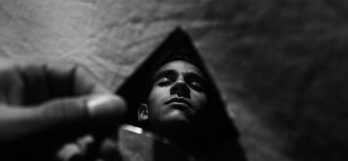 Reflejo de una persona en un espejo triangular que distorsiona la imagen en un entorno urbano