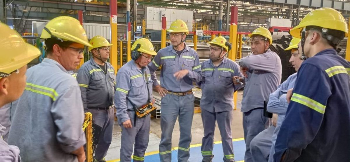 Obreros con cascos en asamblea dentro de una fábrica metalúrgica